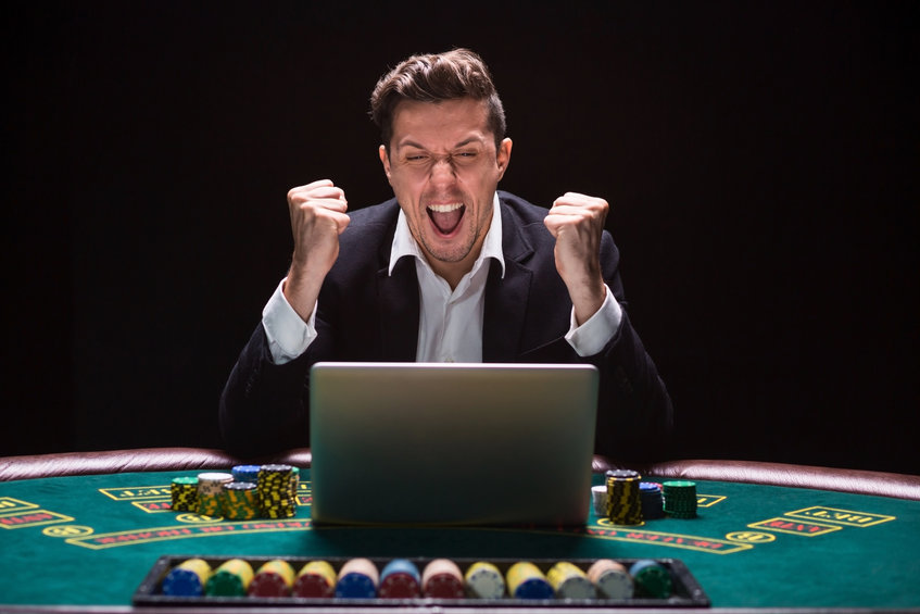Online poker players sitting at the table. He plays on laptop. he won and is happy, and fool. success Online poker players sitting at the table, août 2021